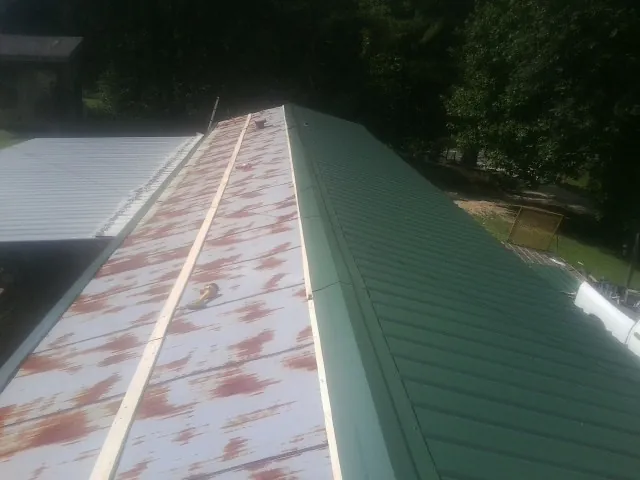 Old rusted panels beside newly installed green metal roofing — Wind Damage Roof Repair by Roofing Brothers in White Earth