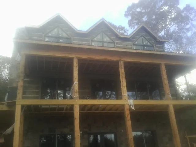 Dormers and porch framing on a large log home under construction — Roof Coating work by our crew in White Earth
