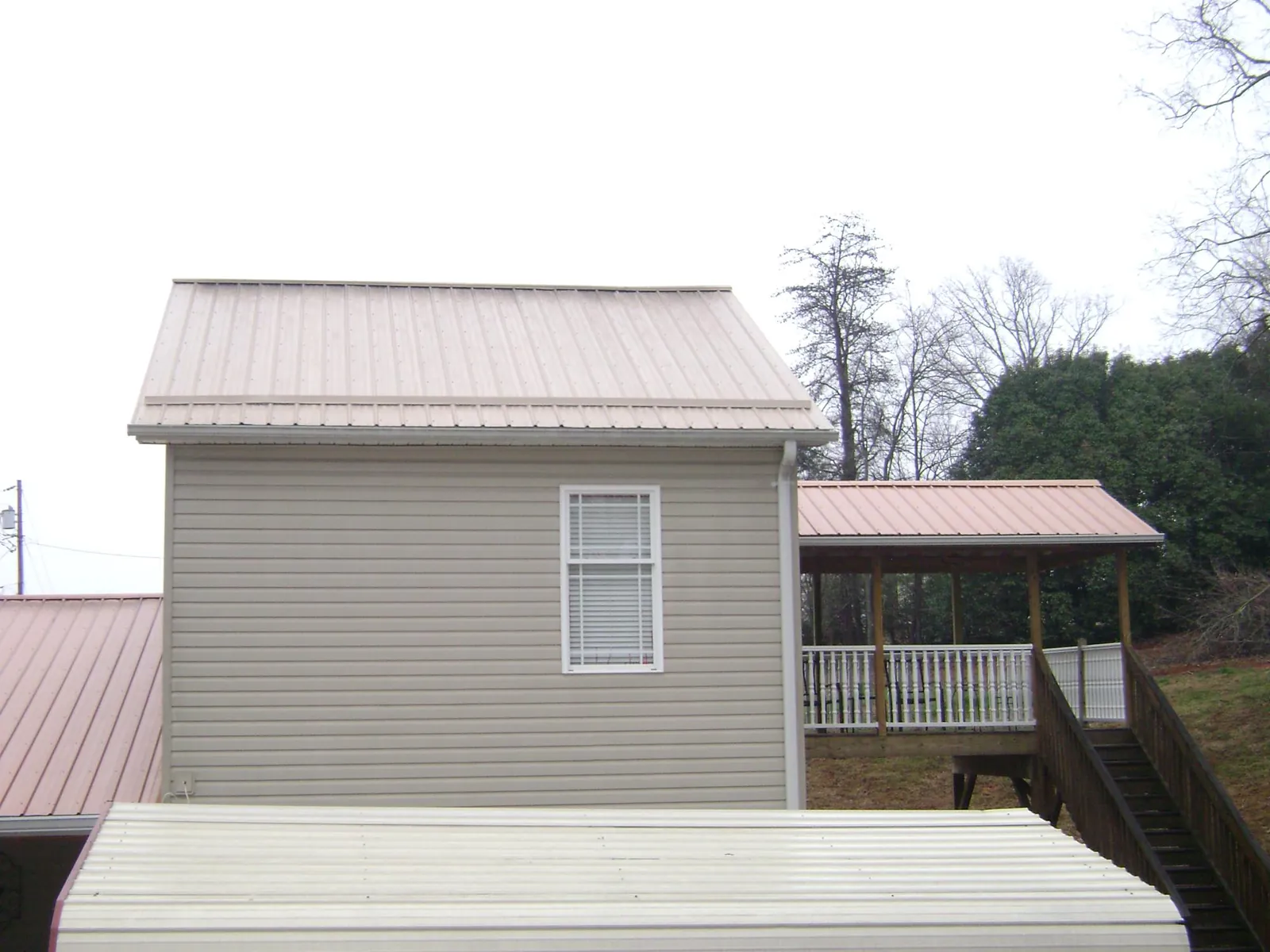 Tan metal roofs on a two story addition and attached porch, from a Roof Replacement job in White Earth